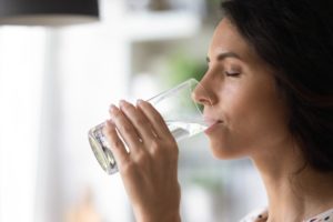 woman drinking water learning benefits of detox