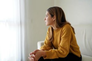 Woman looks out window pensively, thinking about signs of heroin abuse