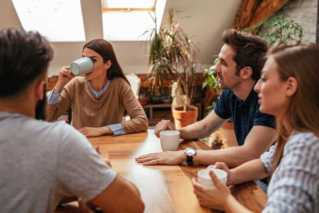 a group of people sit around a table and drink coffee discussing a women's rehab program