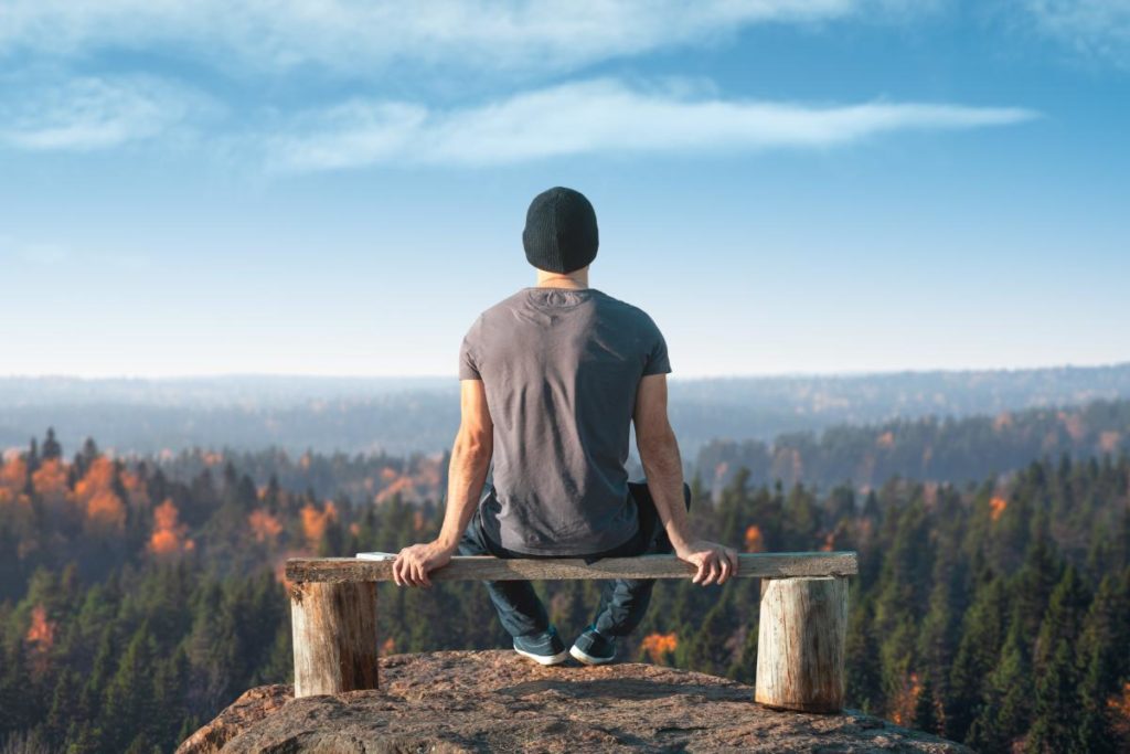 Man sits on bench after hike, after reading up on tips to stay sober