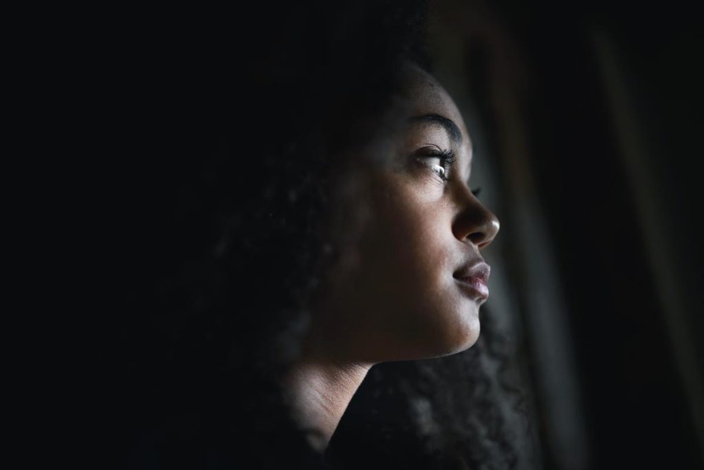 Woman looks out window, pondering common signs of a relapse