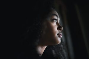Woman looks out window, pondering common signs of a relapse
