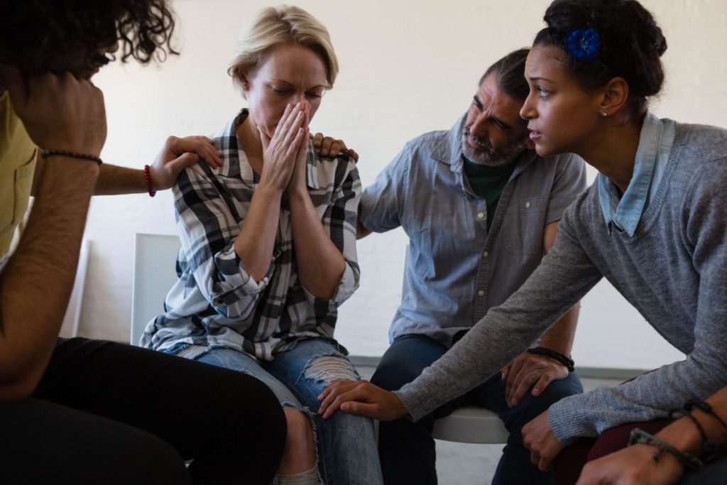 a group of people comfort a person who is crying while learning what is intensive outpatient program