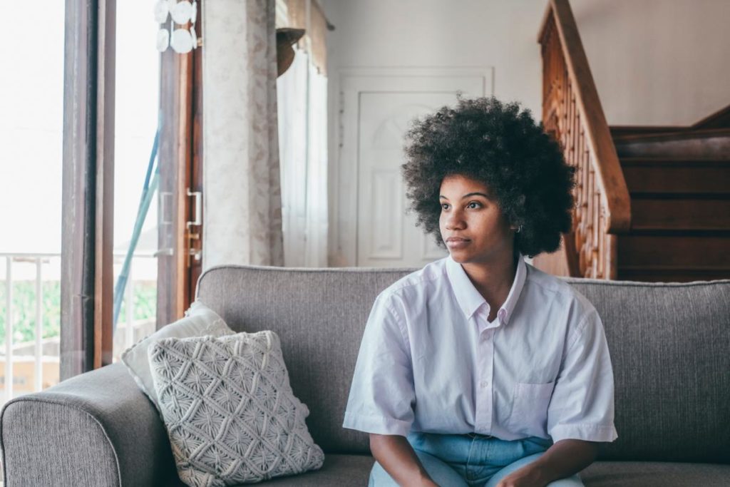 a person with curly hair sits on a couch wondering what is marijuana dependence